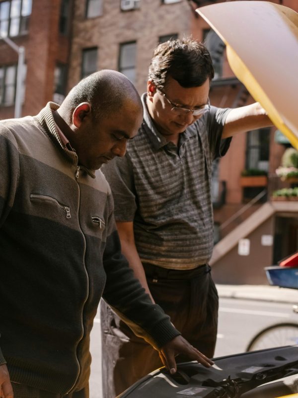 Two men in front of a car with the hood open